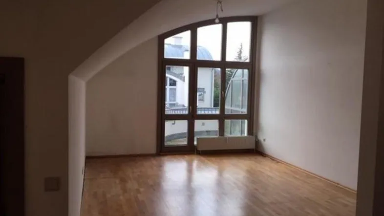 Helles Wohnzimmer mit großen Fenstern, Holzboden und Dachschräge, bietet viel natürliches Licht.