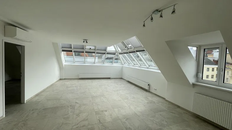 Helles Dachgeschosszimmer mit Fliesenboden, schrägen Wänden und vielen Dachfenstern für viel Tageslicht.