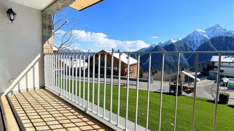 Heller Balkon mit Holzboden, modernem Geländer und beeindruckendem Bergblick.