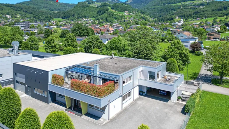 Luftaufnahme eines modernen Gebäudekomplexes mit Flachdach und begrünten Terrassen in ländlicher Umgebung.
