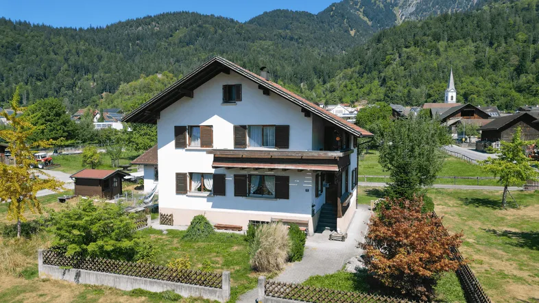 Traditionelles Einfamilienhaus mit Satteldach und Bergblick in ländlicher Umgebung.