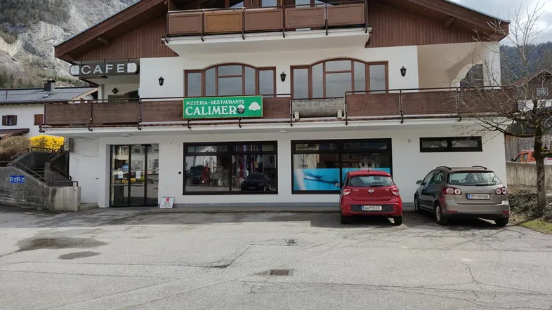 Gebäude mit Pizzeria-Restaurant im Erdgeschoss und Wohnungen darüber, umgeben von Bergen.