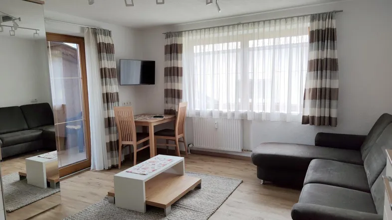 Gemütlicher Wohn-Essbereich mit bequemer Eckcouch, Esstisch und Zugang zum Balkon.
