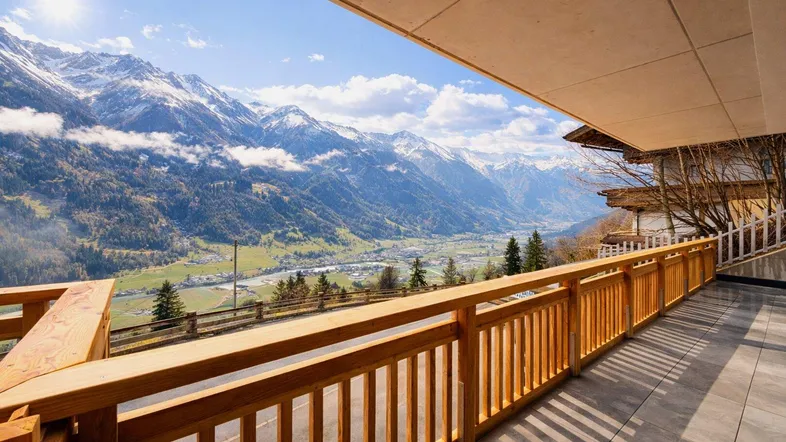 Große Terrasse mit Holzbalkongeländer und atemberaubendem Blick auf die schneebedeckten Berge und das Tal.