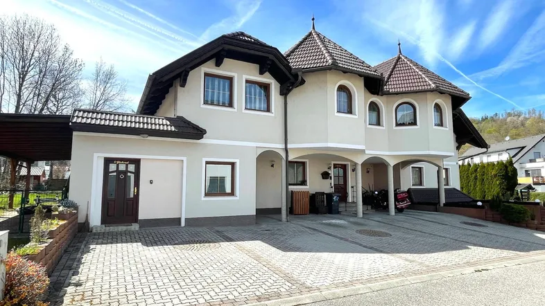 Die Vorderseite des Hauses mit gepflasterter Auffahrt und überdachtem Eingangsbereich.