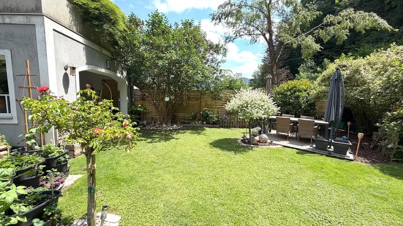 Gepflegter grüner Garten mit Essbereich im Freien, umgeben von Bäumen und Sträuchern.