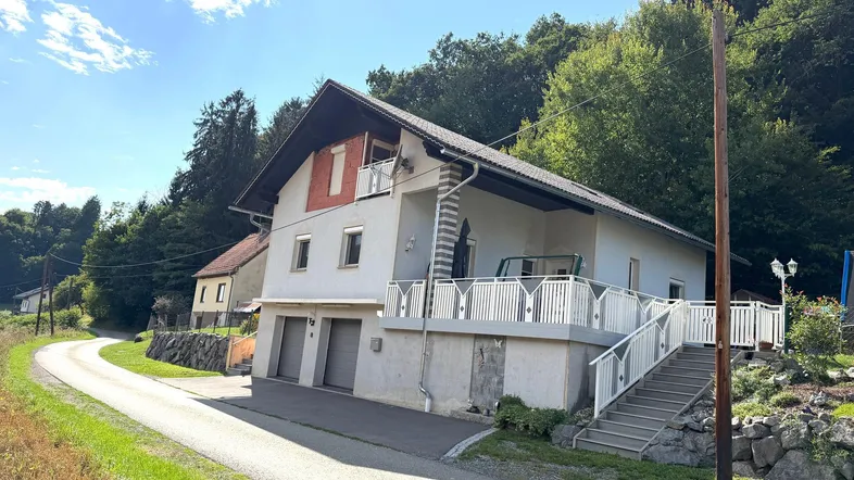 Hausfassade mit großer Terrasse und Blick auf die umliegende Natur und Hügel.