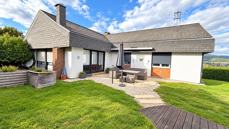 Haus mit gepflegtem Garten, Terrasse und weitem Blick auf die umliegende Landschaft.