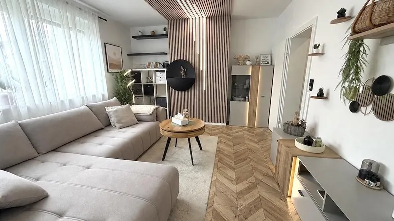 Modernes Wohnzimmer mit beigem Ecksofa, Holzlamellenwand und Fischgrätparkettboden.