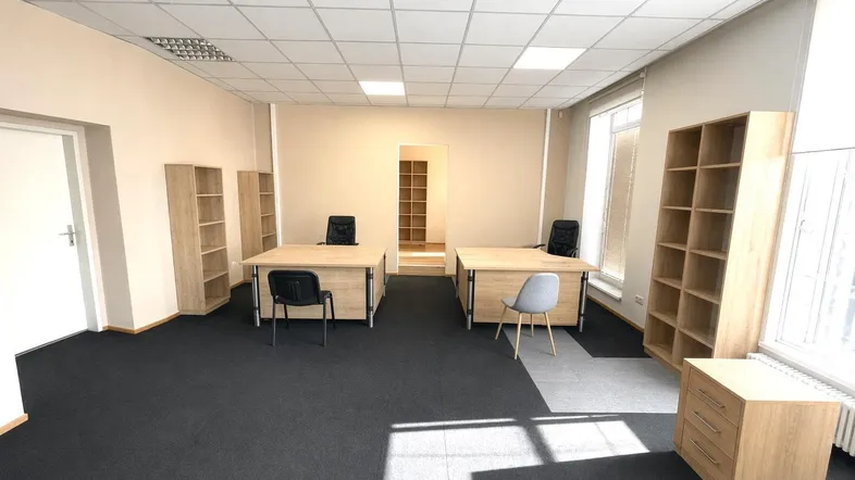 Geräumiges Büro mit mehreren Arbeitsplätzen, Teppichboden und großen Fenstern für viel Tageslicht.
