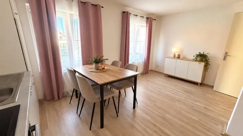 Heller Essbereich mit modernem Holztisch, bequemen Stühlen und rosa Vorhängen, Teil eines offenen Wohnkonzepts.