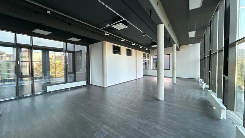 Großer, offener Büroraum mit hohen Decken, großen Fenstern und modernem Design.