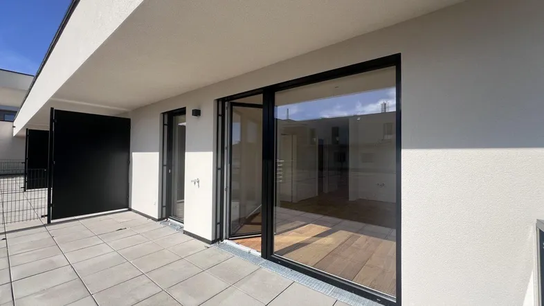 Geräumige Terrasse mit modernen Fliesen und Zugang zu den Innenräumen, ideal für entspannte Stunden im Freien.