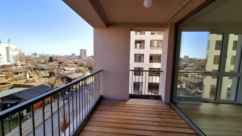 Geräumiger Balkon mit Holzboden und Blick auf die Stadt und umliegende Gärten.