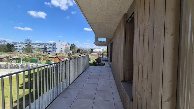 Langer Balkon mit Fliesenboden und Metallgeländer, bietet einen weiten Blick auf die Umgebung.