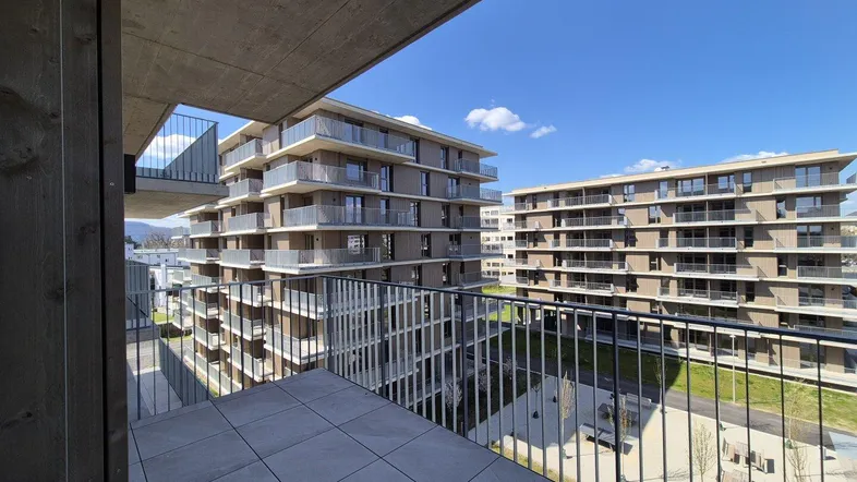 Geräumiger Balkon mit Fliesenboden und Blick auf die umliegenden Wohngebäude und Grünflächen.