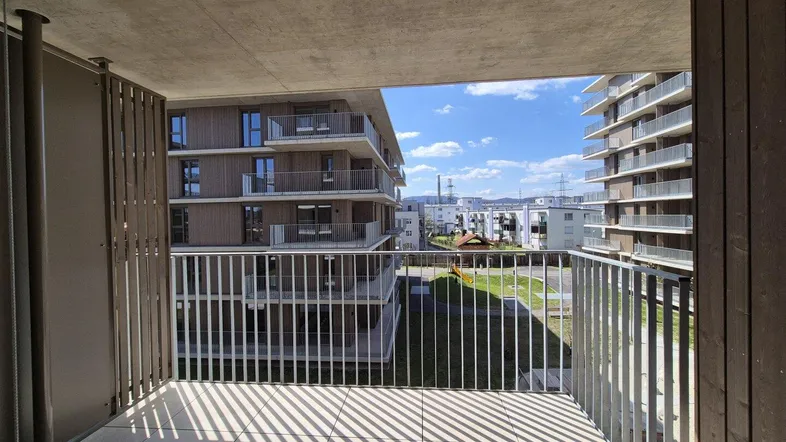 Geräumiger Balkon mit Fliesenboden und Blick auf die umliegenden modernen Wohngebäude.