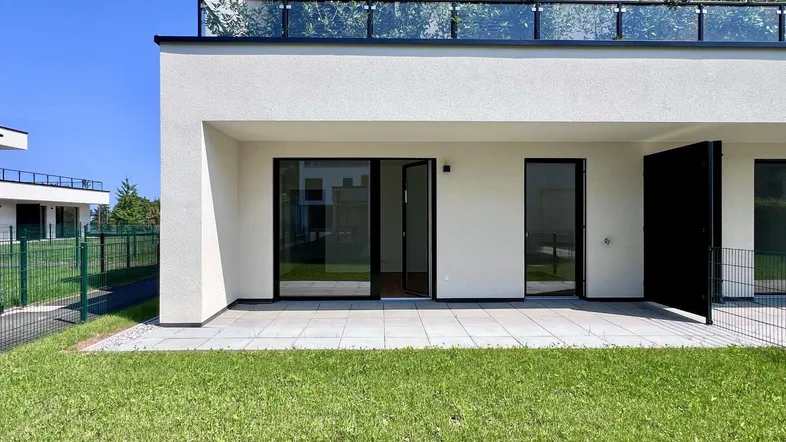 Moderne Erdgeschosswohnung mit großer Terrasse, Rasenfläche und direktem Zugang zum Garten.