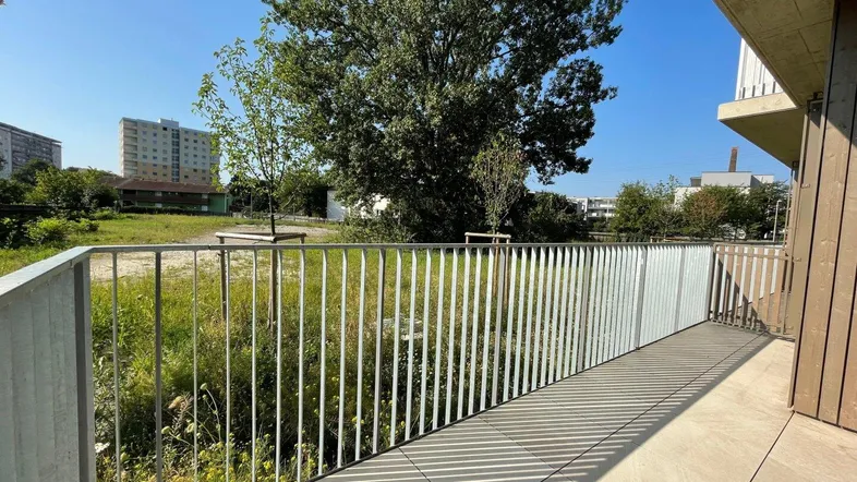 Sonnige Terrasse mit Blick ins Grüne und auf die umliegende Wohnbebauung, ideal zum Entspannen.