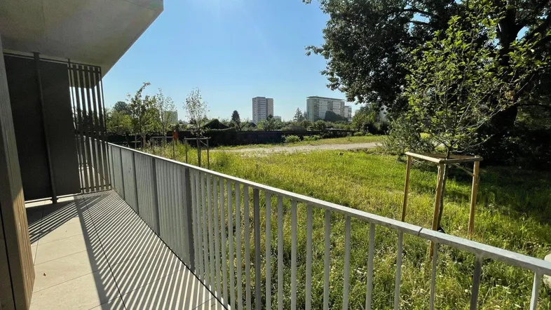 Heller Balkon mit Blick ins Grüne und auf die umliegende Stadtlandschaft an einem sonnigen Tag.