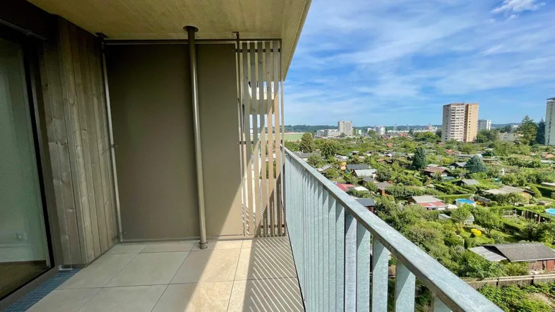 Geräumiger Balkon mit Fliesenboden und weitem Blick über die Stadt und Kleingärten.