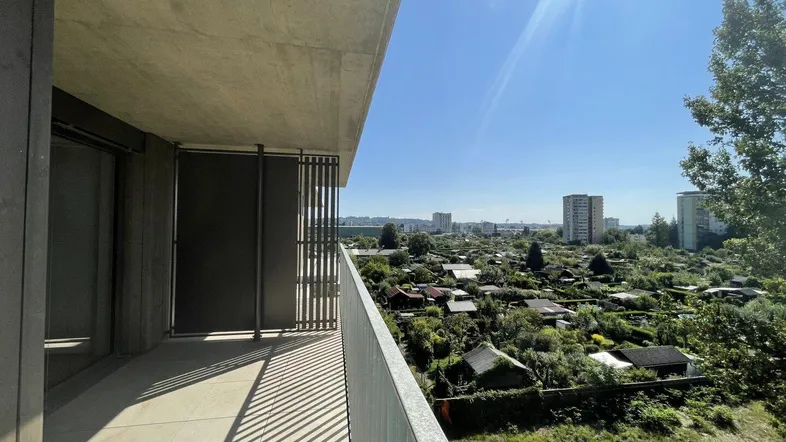 Heller Balkon mit Fliesenboden und weitem Blick über die Stadt und Kleingärten.