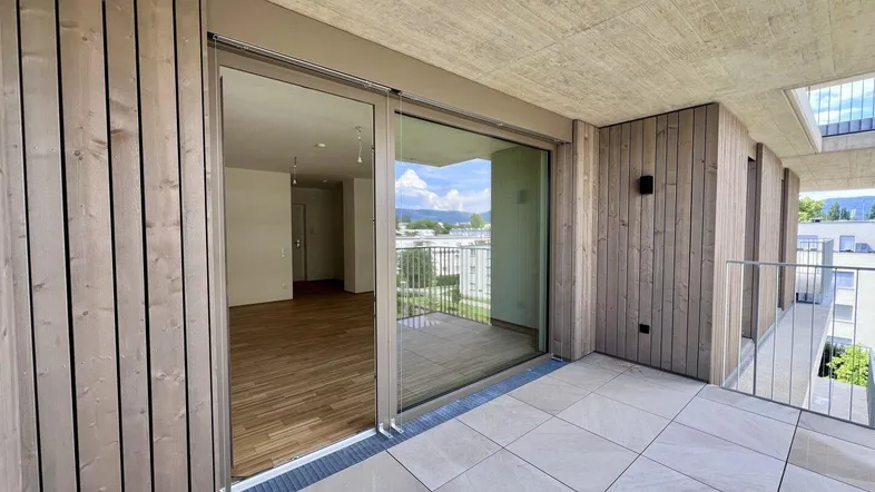 Geräumiger Balkon mit Fliesenboden und Blick auf die Umgebung, verbunden mit dem Wohnbereich.