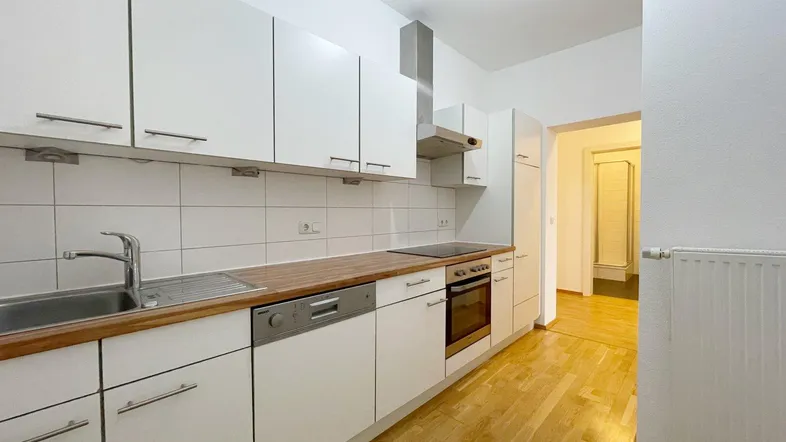 Funktionale Küche mit weißen Schränken, Holz-Arbeitsplatte und integrierten Geräten.