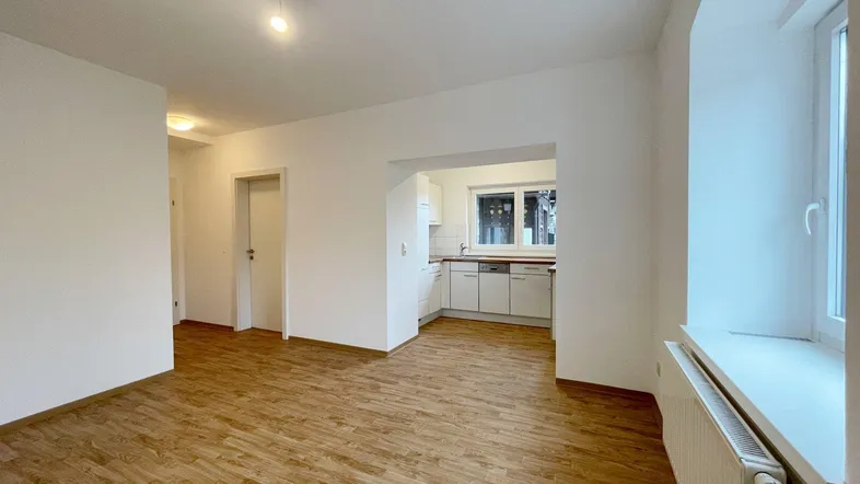 Helles Wohnzimmer mit Holzboden und offenem Zugang zu einer modernen Küchenzeile.