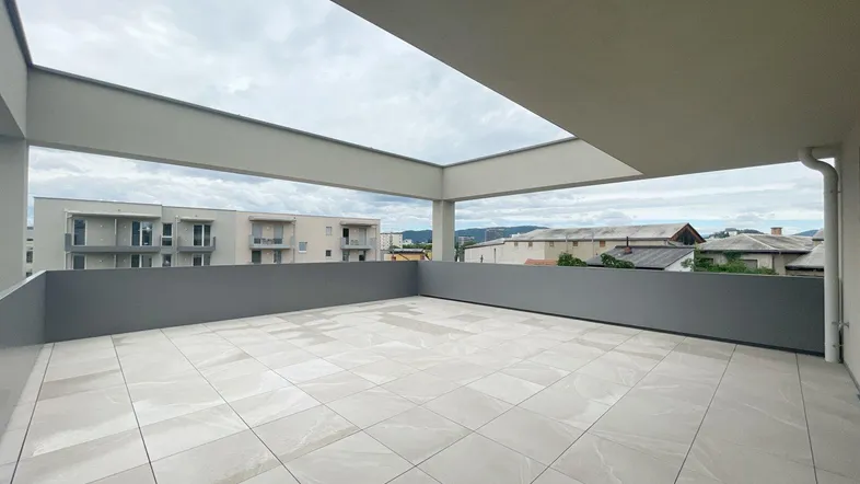 Geräumige, geflieste Terrasse mit moderner grauer Brüstung und Blick auf die umliegende Bebauung.
