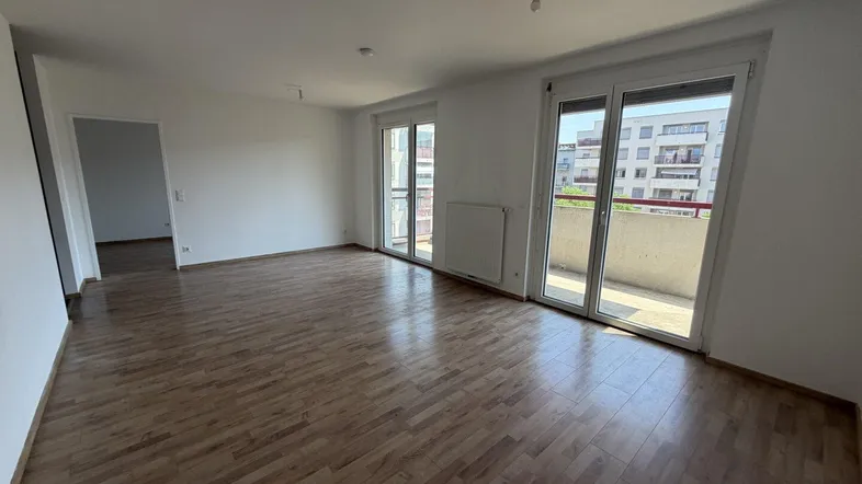 Helles Wohnzimmer mit Laminatboden und Zugang zu einem Balkon, ideal für entspannte Stunden.