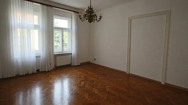Helles Zimmer mit Fischgrätparkett und großen Fenstern, bereit zur individuellen Gestaltung.