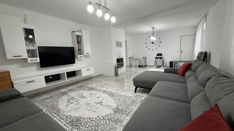 Geräumiges Wohnzimmer mit großem Ecksofa, modernem TV-Möbel und Kaminbereich.