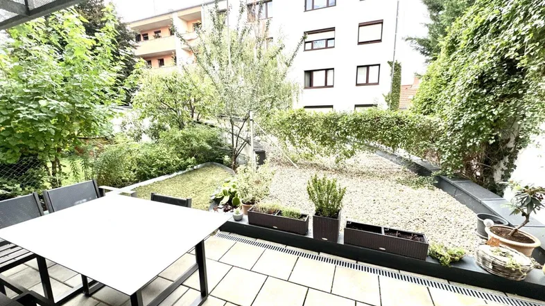 Geräumige Terrasse mit Essbereich und Blick auf den begrünten Gartenbereich des Anwesens.