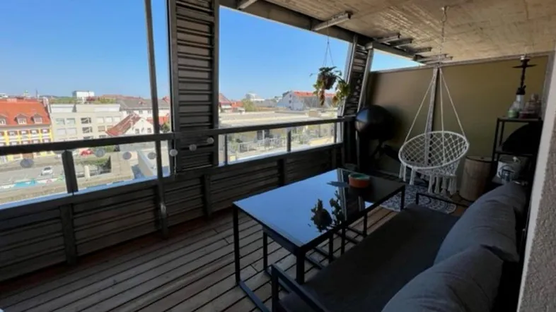Geräumiger Balkon mit Holzfußboden, bequemen Möbeln und weitem Blick über die Stadt.