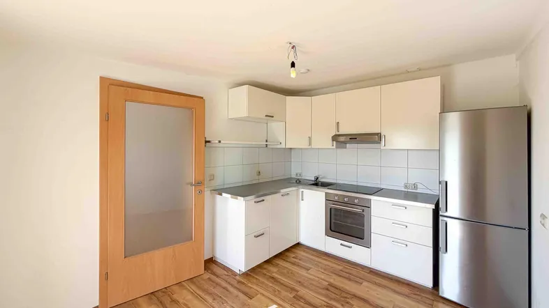 Funktionale Küche mit weißen Schränken, integriertem Backofen und Kühlschrank.