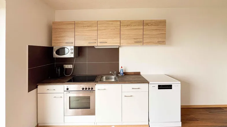 Moderne Einbauküche mit hellen Holzschränken, weißen Unterschränken und integrierten Geräten.