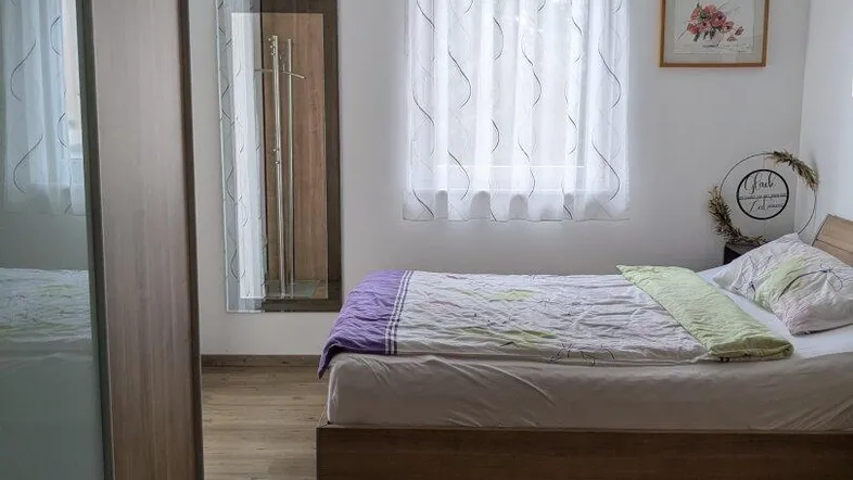 Helles Schlafzimmer mit Holzbett, großem Kleiderschrank und Laminatboden.