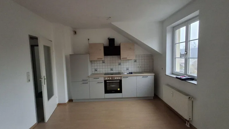 Helle offene Küche mit Dachschräge, Einbauküche und Laminatboden in einem modernen Wohnraum.