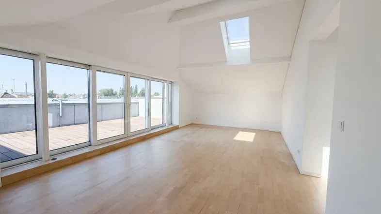 Heller, geräumiger Wohnbereich mit Holzboden, großen Fenstern und Zugang zur Dachterrasse.