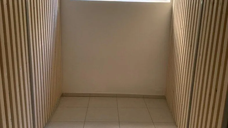 Kellerraum mit Fenster, gefliestem Boden und Holzlattenwänden für individuelle Abteile.