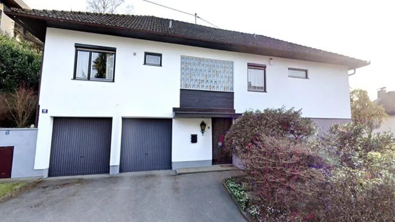 Vorderansicht eines Einfamilienhauses mit zwei Garagen und gepflegter Zufahrt.