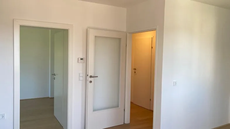 Heller Flur mit mehreren Türen und hellem Holzfußboden, der zu weiteren Räumen führt.