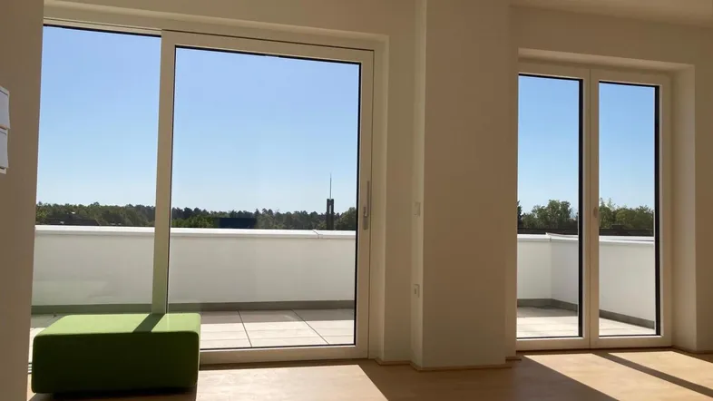 Heller Wohnbereich mit großen Schiebetüren, die auf eine sonnige Terrasse führen und weitem Blick.