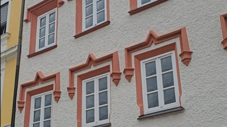 Historische Fassade eines Gebäudes mit kunstvollen Fensterrahmen und traditioneller Architektur.