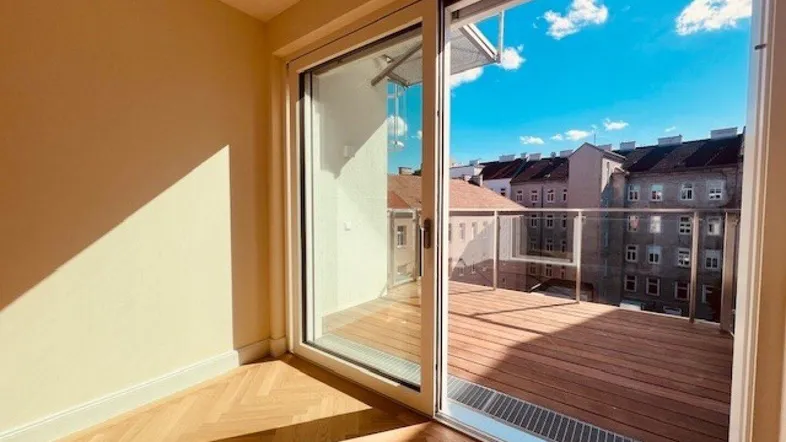 Heller Innenraum mit Fischgrätparkett und großem Schiebefenster zur Holzterrasse.