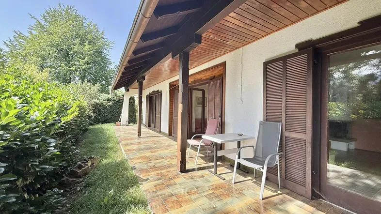 Überdachte Terrasse mit Fliesenboden und Gartenmöbeln, ideal für entspannte Stunden im Freien.