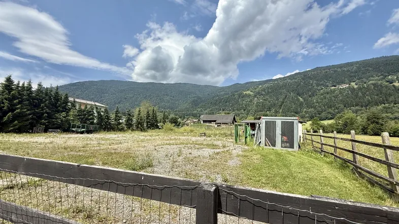 Weitläufiges Grundstück mit Blick auf die umliegende Berglandschaft und grüne Natur unter blauem Himmel.