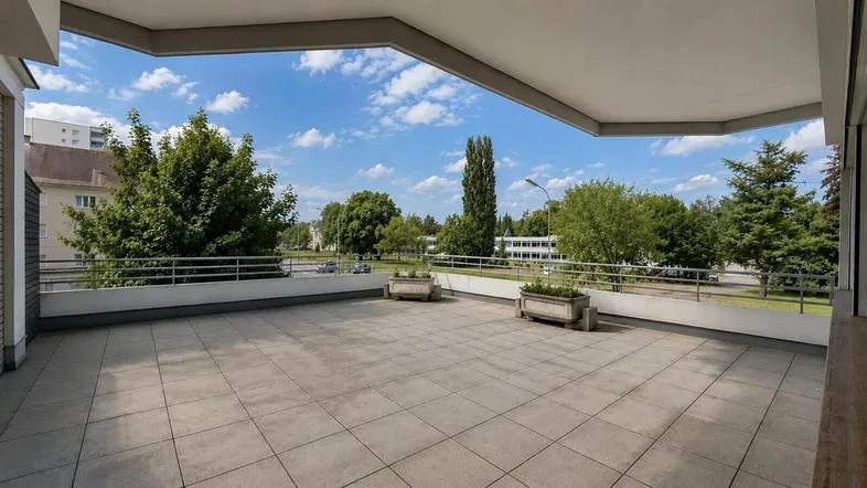 Großzügige Außenterrasse mit weitem Blick auf die grüne Umgebung und die umliegenden Gebäude.