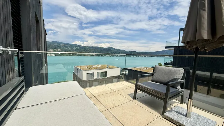 Große Terrasse mit bequemen Lounge-Möbeln und atemberaubendem Blick auf den See und die Berge.